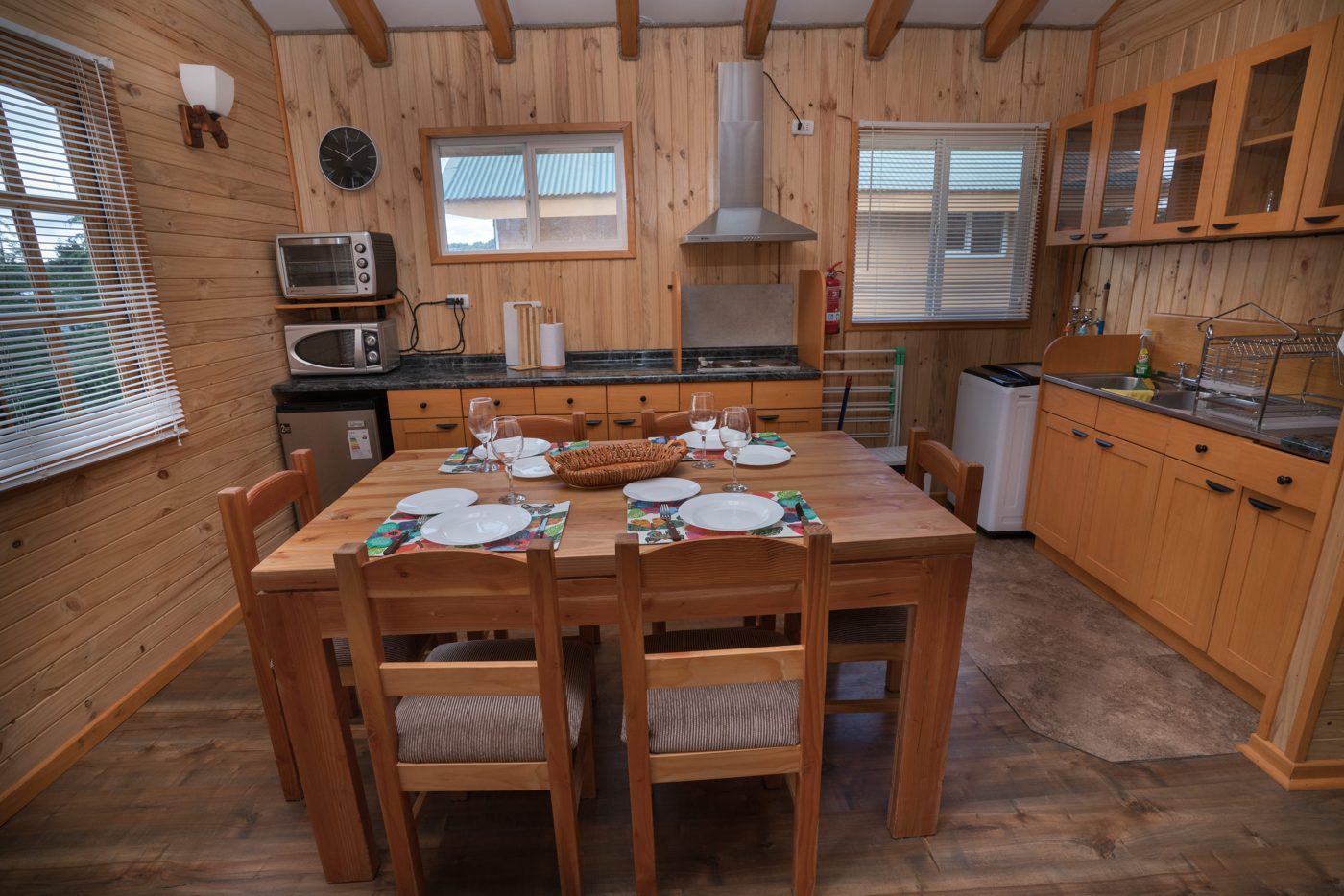 Cocina y comedor de una cabaña Rilamar, con mesa de madera puesta para seis