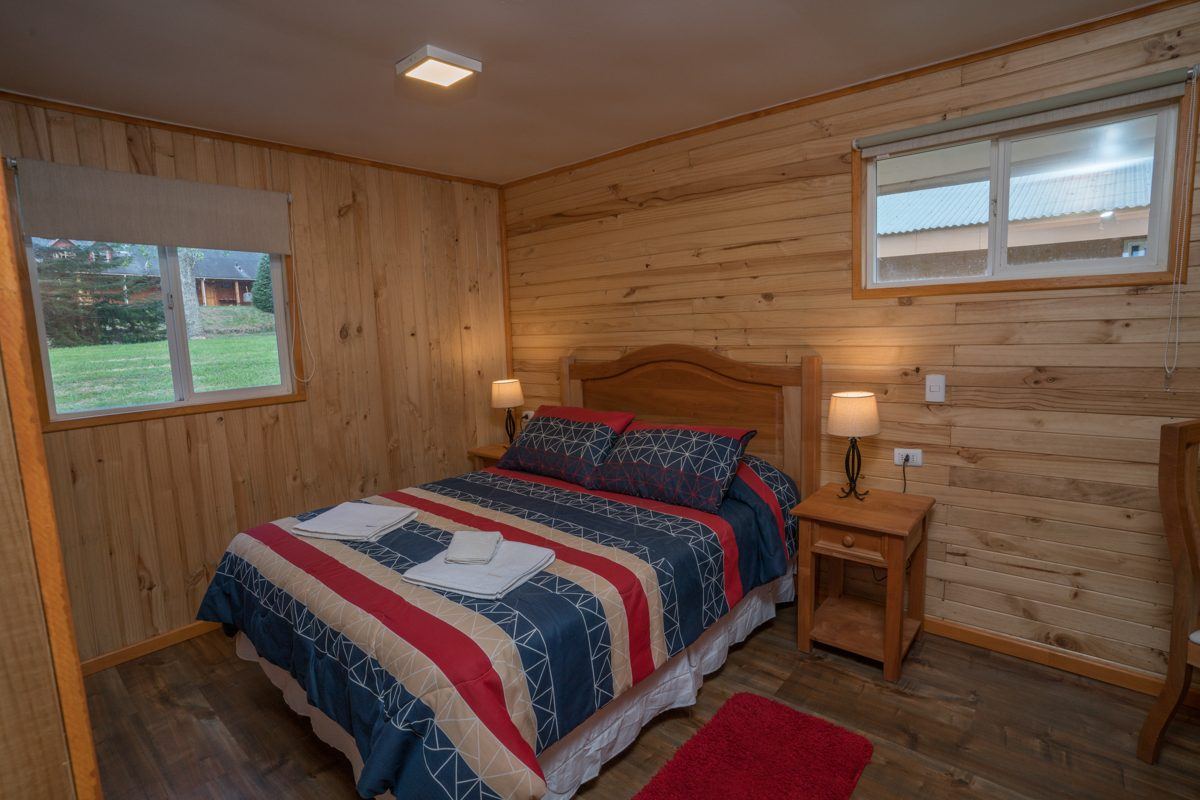 Dormitorio principal con cama de dos plazas, veladores y ventana al jardín