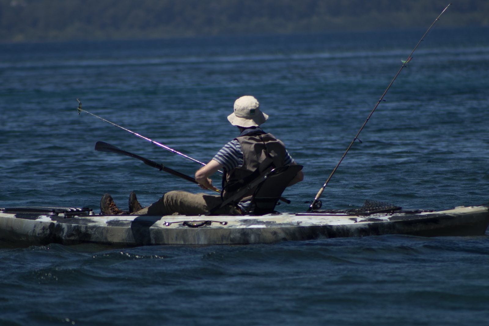 Pescador en kayak remando en el Lago Llanquihue, con cañas de pesca a bordo