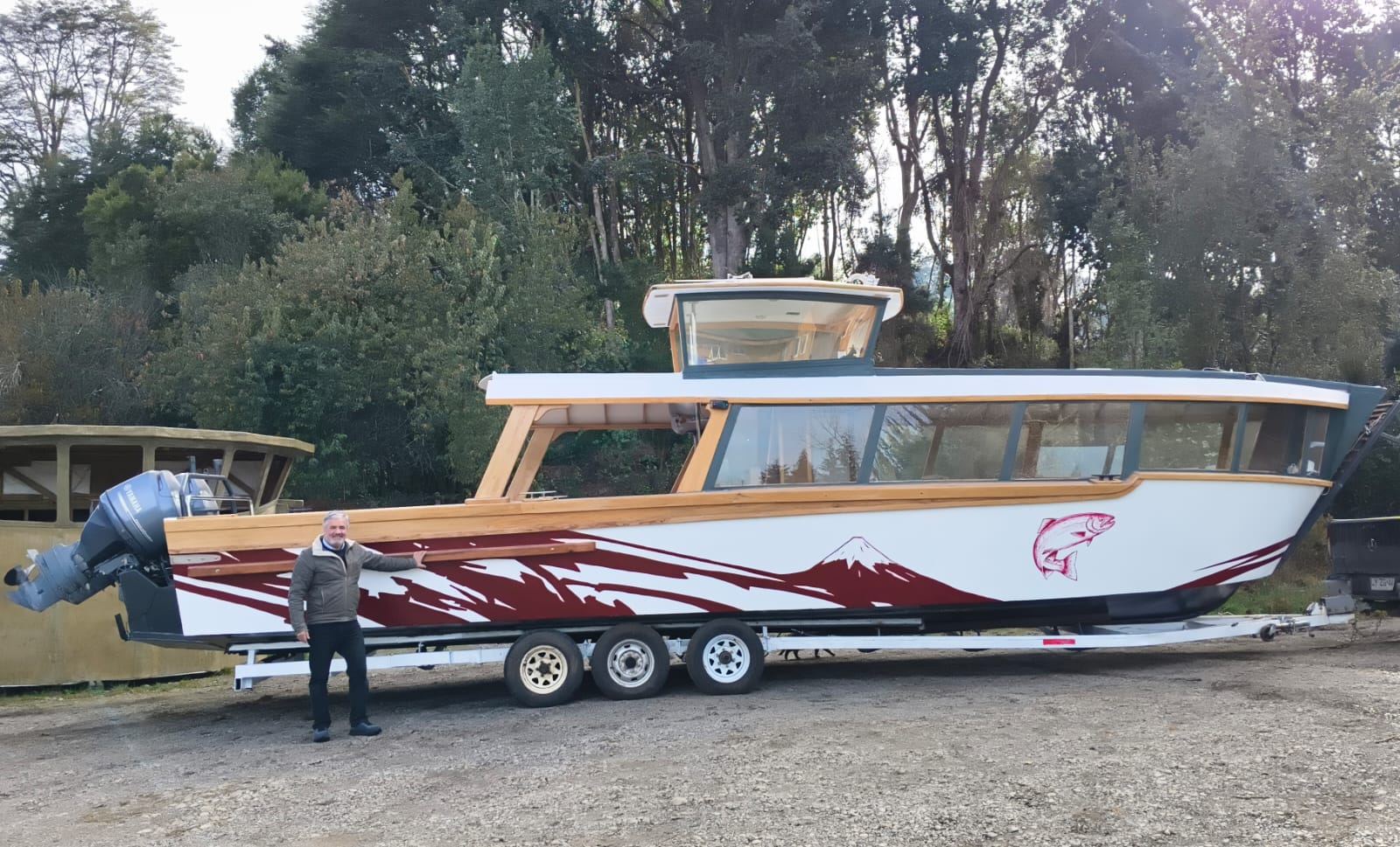 Lancha Lago Llanquihue, de 12 metros, con casco blanco, cabina de madera y diseño del volcán Osorno y una trucha
