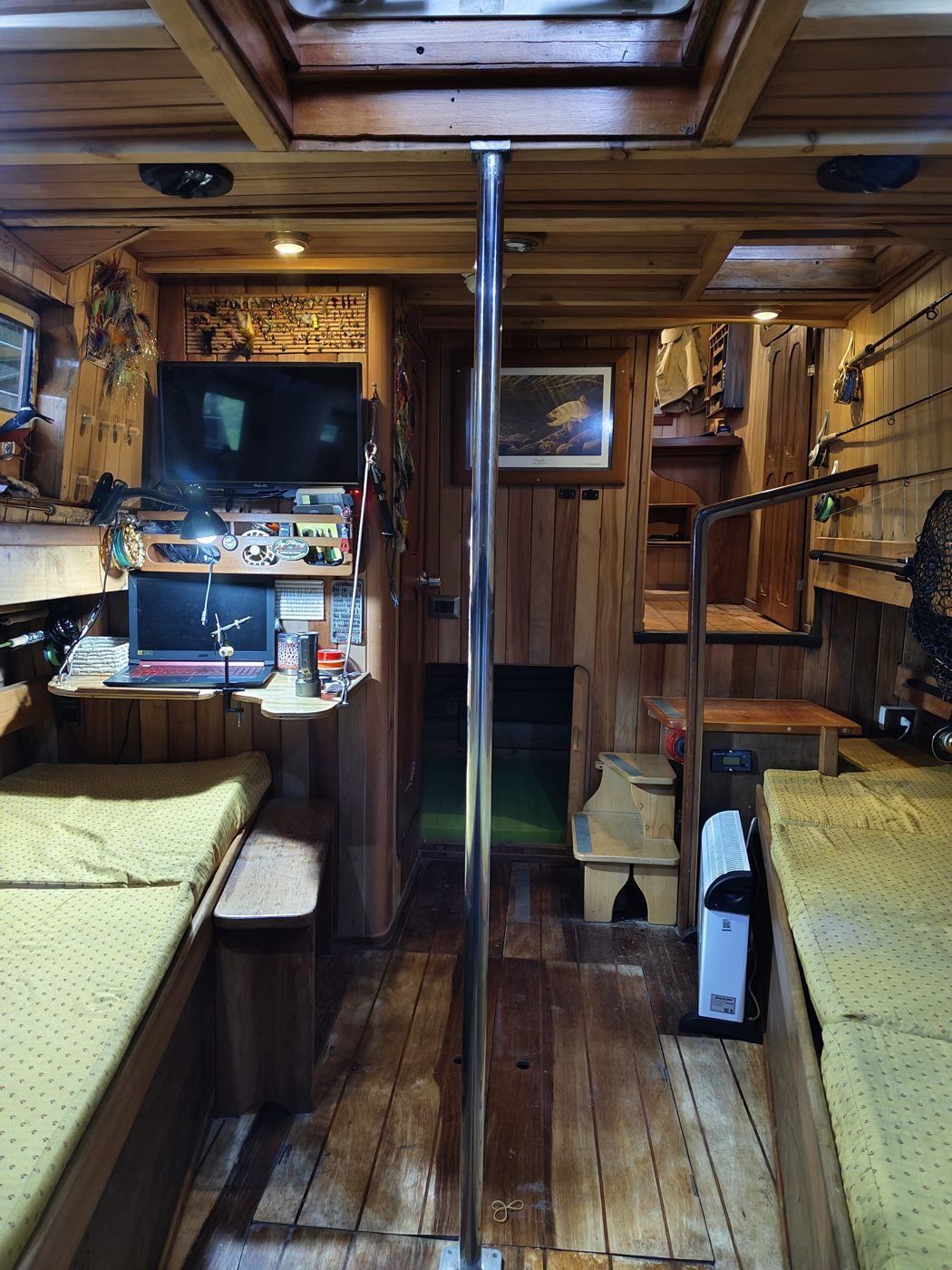 Interior del Lithium: cabina en madera con asientos, cañas de pesca y equipo para atar moscas