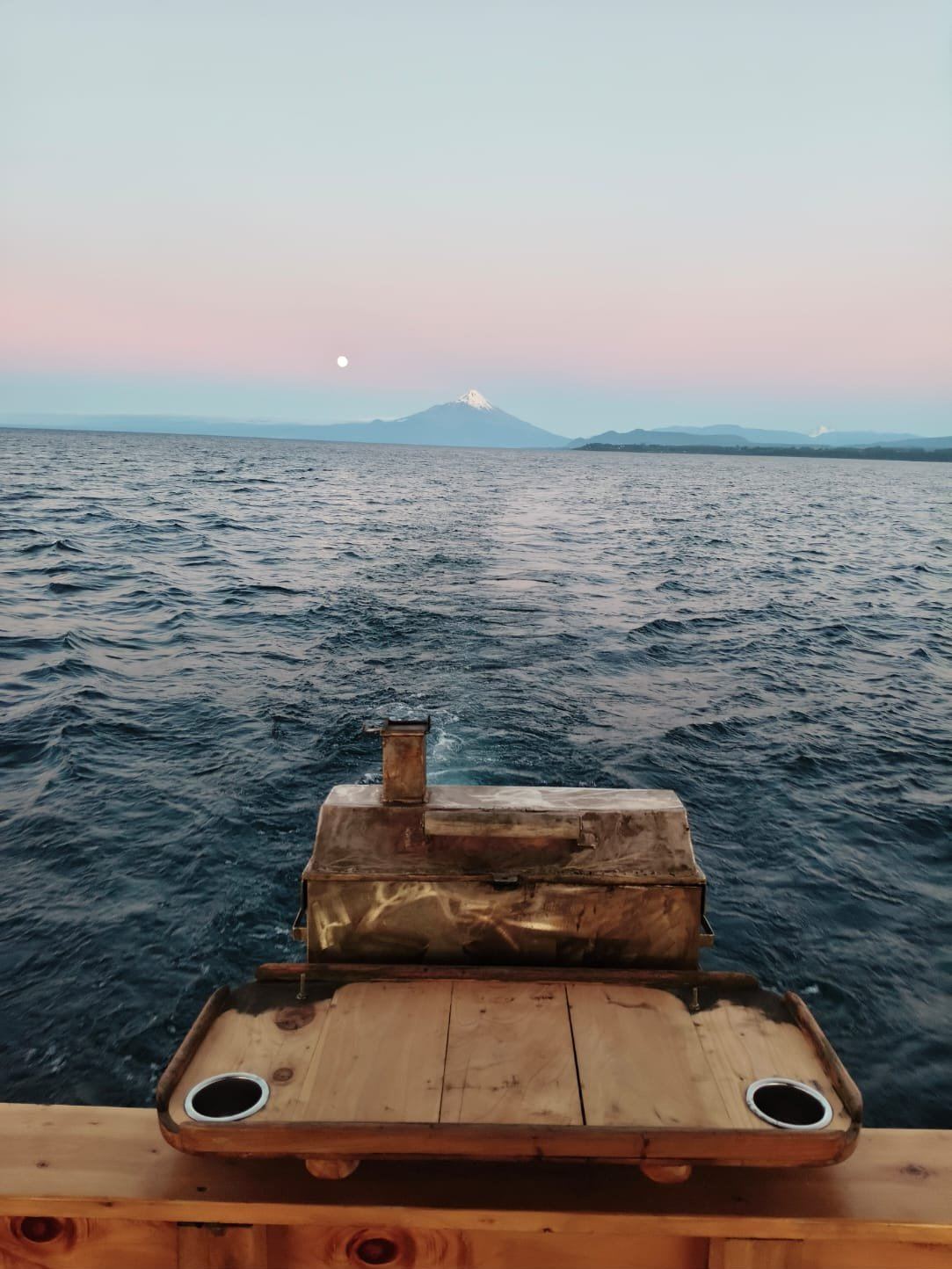 Parrilla en la popa del Lithium navegando al atardecer, con el volcán Osorno y la luna al fondo