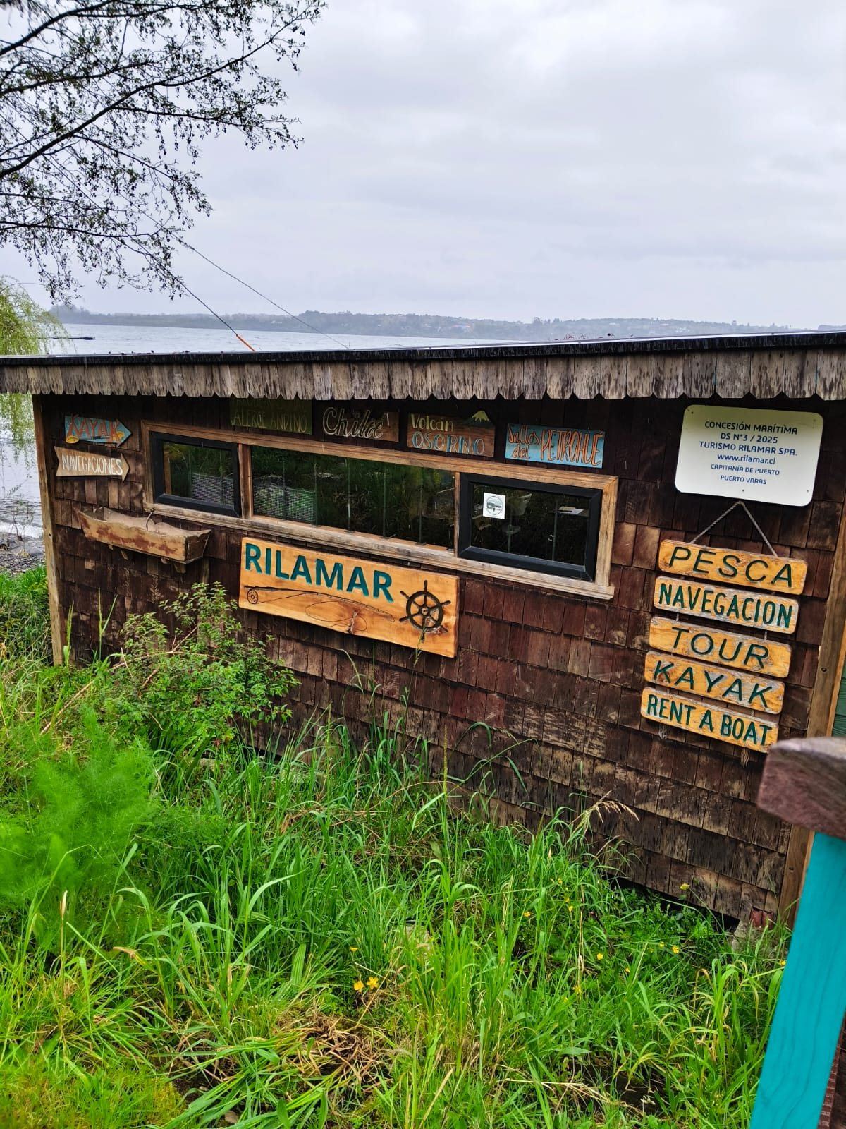 Fachada de la oficina Rilamar con letreros de madera: pesca, navegación, tour, kayak y rent a boat