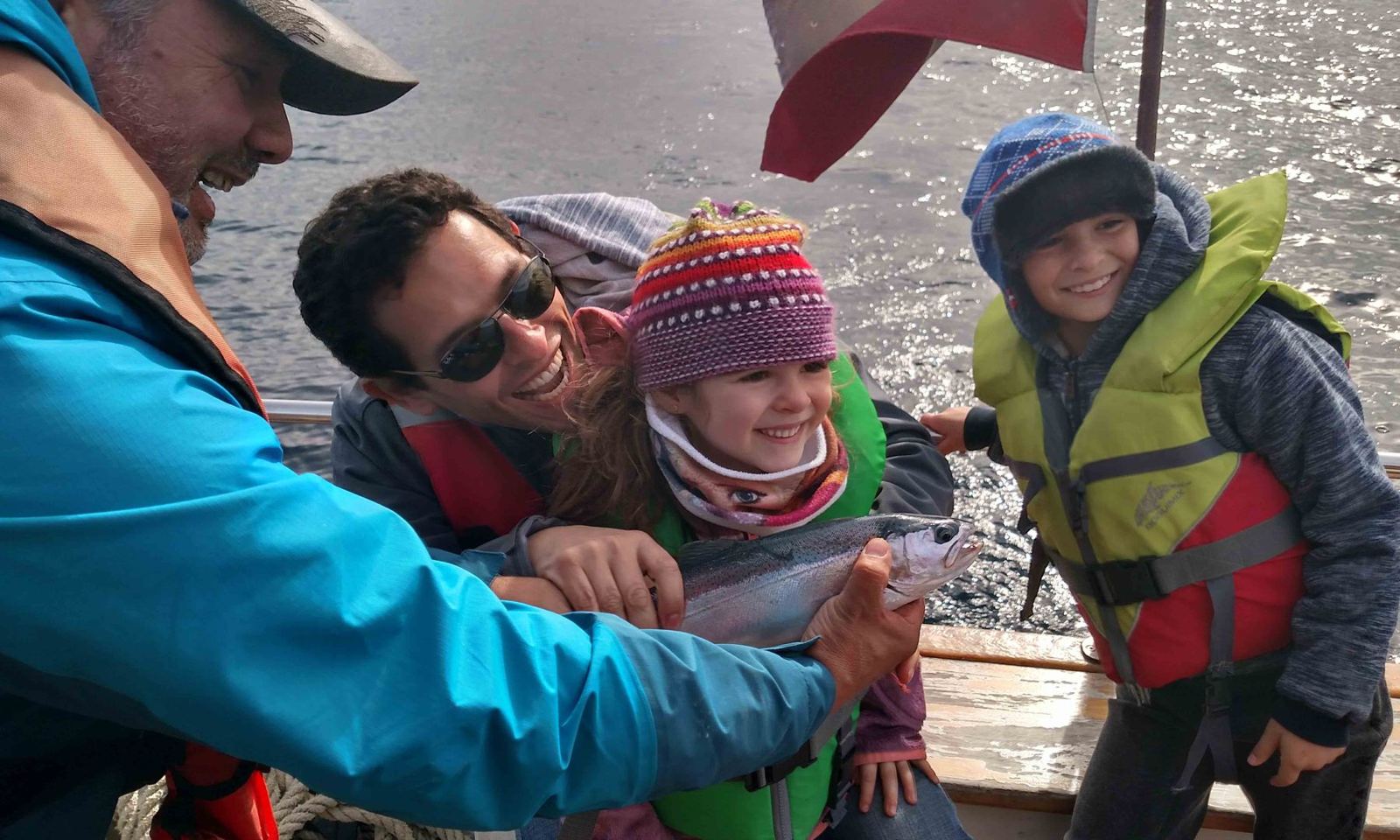 Familia a bordo sosteniendo una trucha recién capturada, antes de devolverla al lago